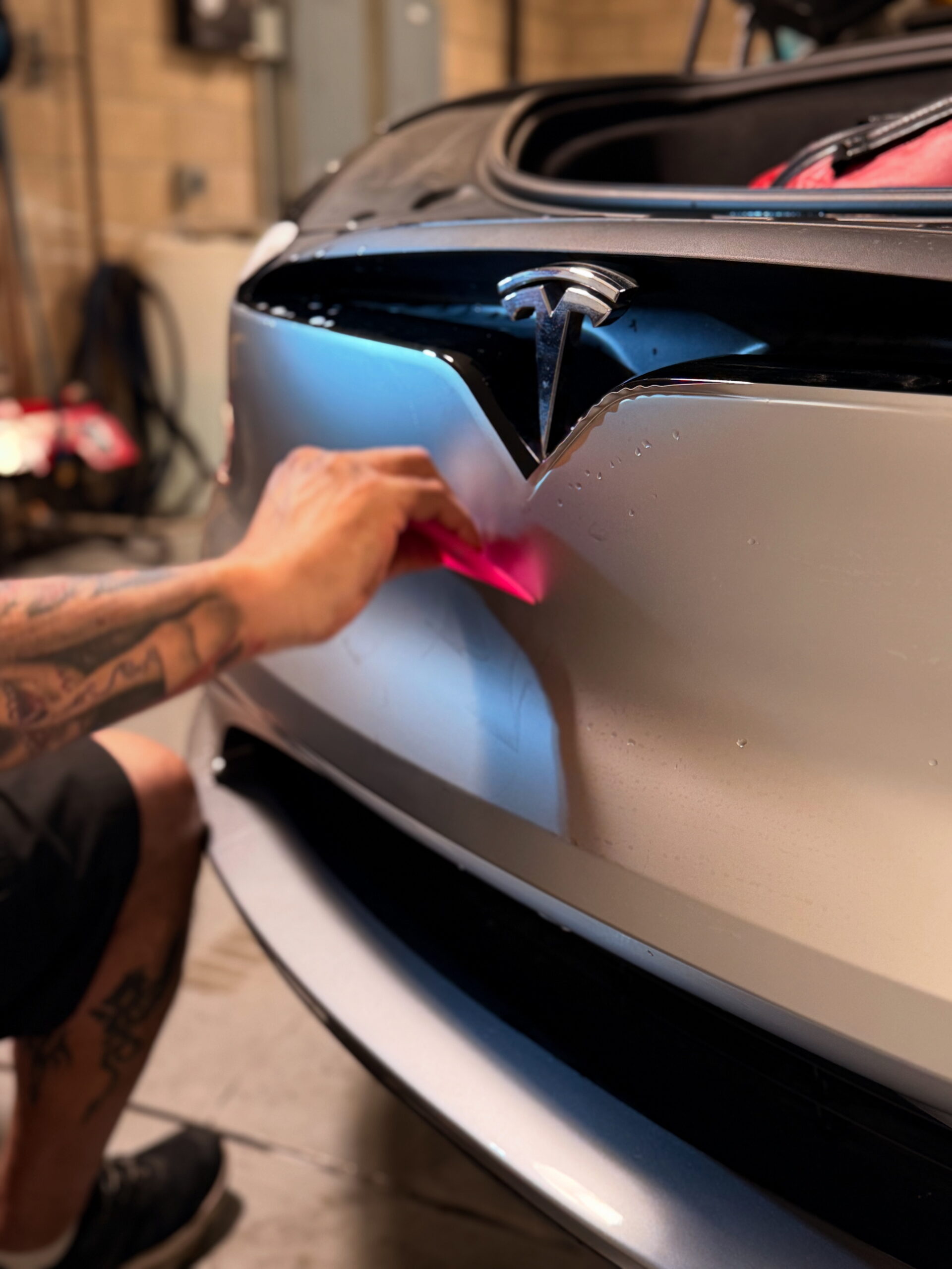 Technician installing satin titanium silver PPF from SVG on a 2025 Tesla model X at CDA auto styling