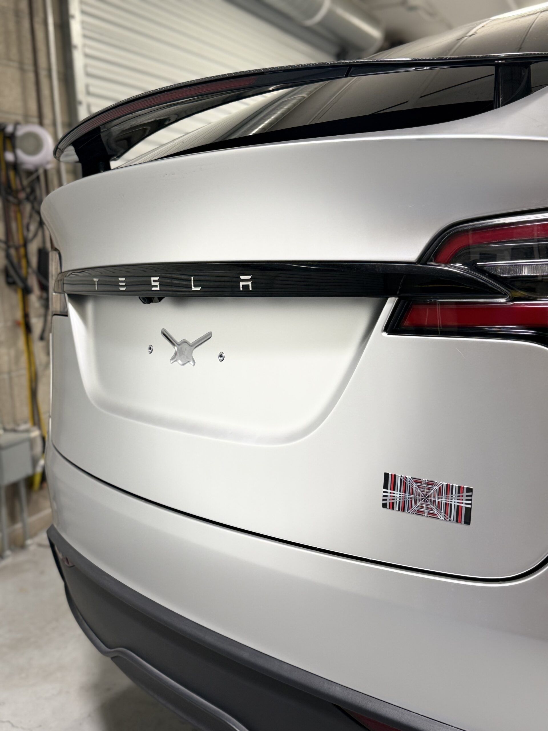 Rear view of a 2025 Tesla model X with SVG paint protection, film in satin titanium, silver, and plaid badge at CDA auto styling