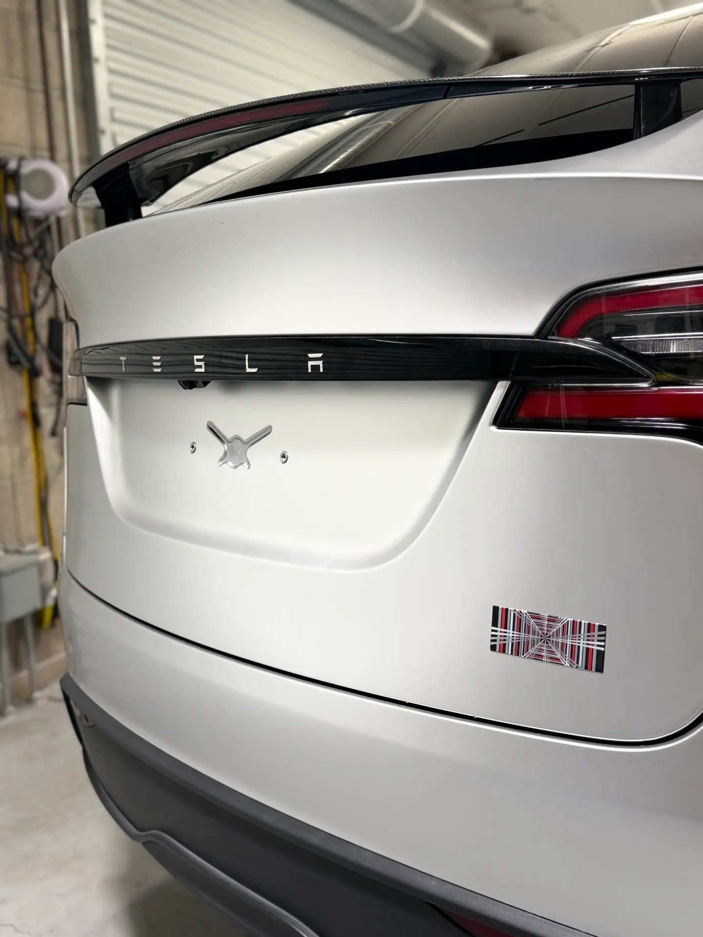 Rear view of a 2025 Tesla model X with SVG paint protection, film in satin titanium, silver, and plaid badge at CDA auto styling
